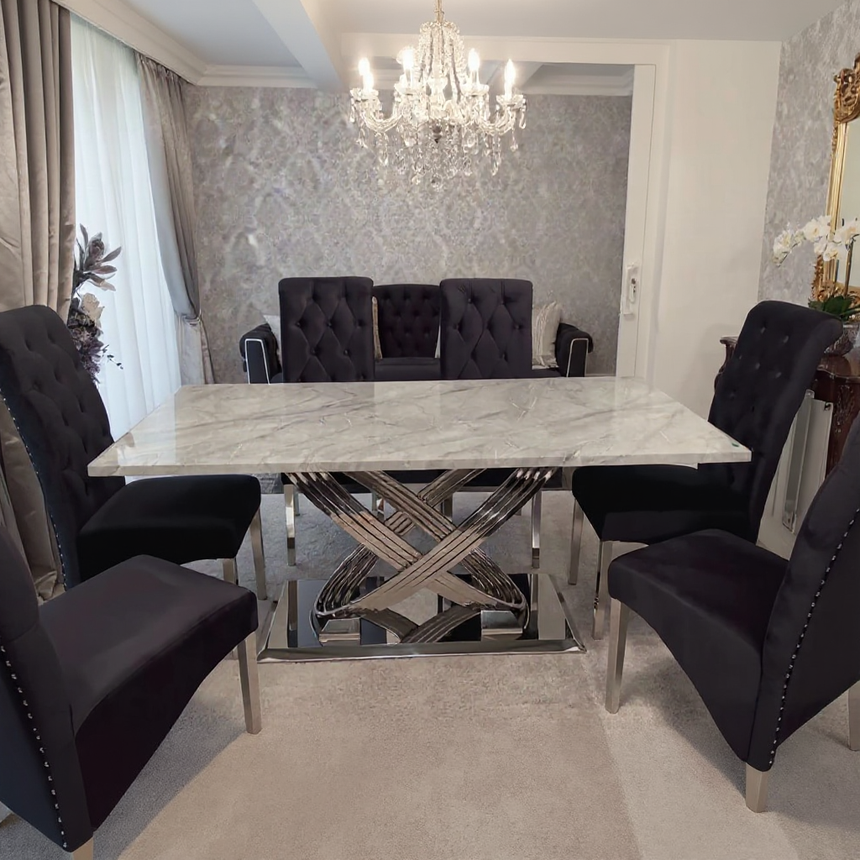 Dining room with a marble table and black chairs, featuring a chandelier.