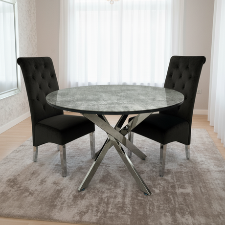 Dining room with a round marble table and black chairs, featuring a chandelier.