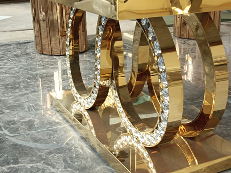 Gold hoop earrings with clear gemstones on a reflective surface